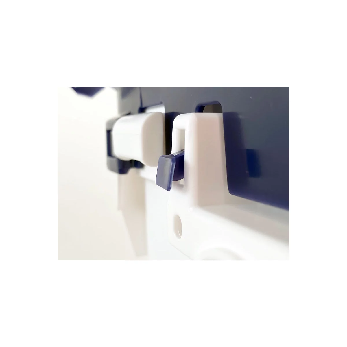 Gros plan d'une pièce en plastique blanc avec un mécanisme de verrouillage bleu.