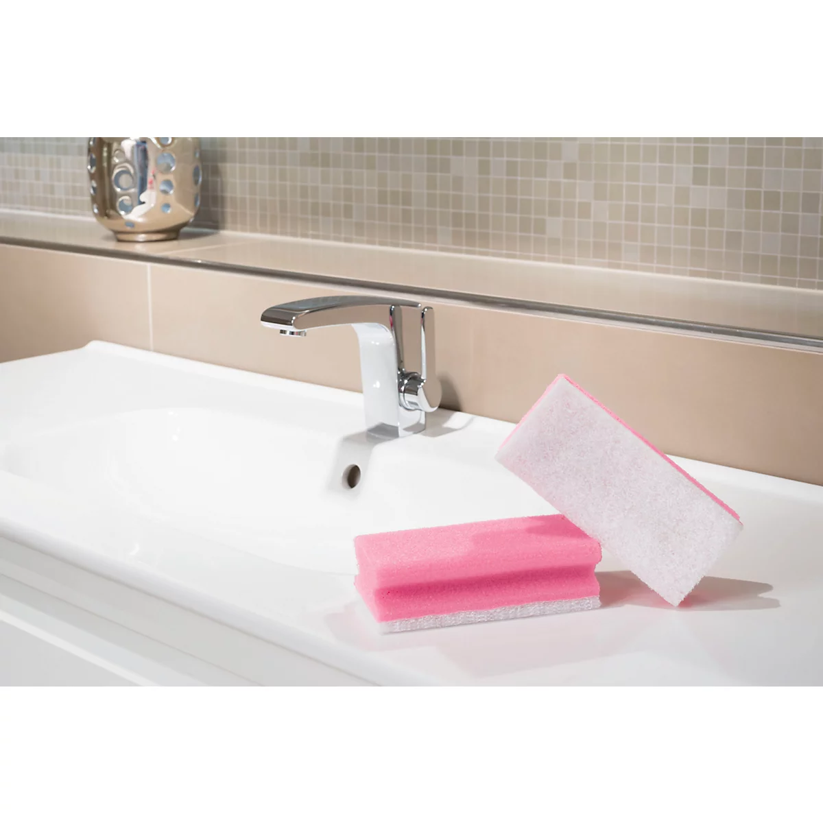 Un lavabo blanc avec un robinet chromé. Deux éponges roses sont sur la surface.