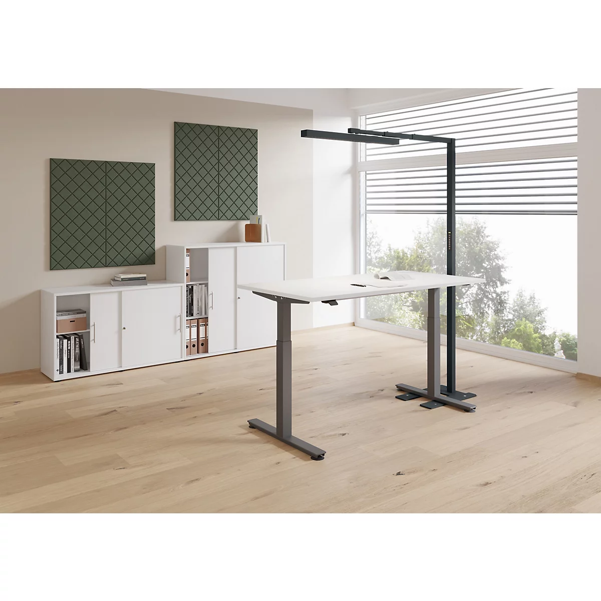 Bureau réglable en hauteur dans un bureau. Une fenêtre et des armoires sont visibles en arrière-plan.