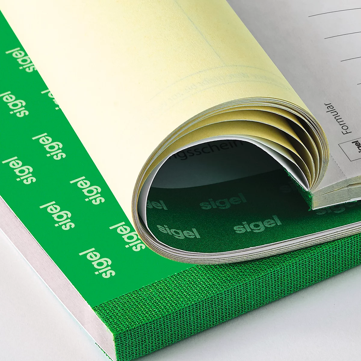 Gros plan d'un carnet partiellement enroulé. La couverture est verte avec l'inscription "sigel" ; les pages sont ivoire.
