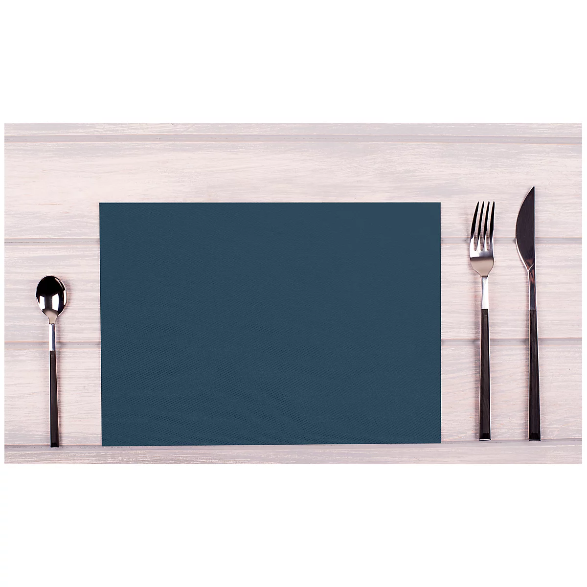 Nappe de table bleu foncé avec couverts sur une surface en bois. Une cuillère à gauche, une fourchette et un couteau à droite.