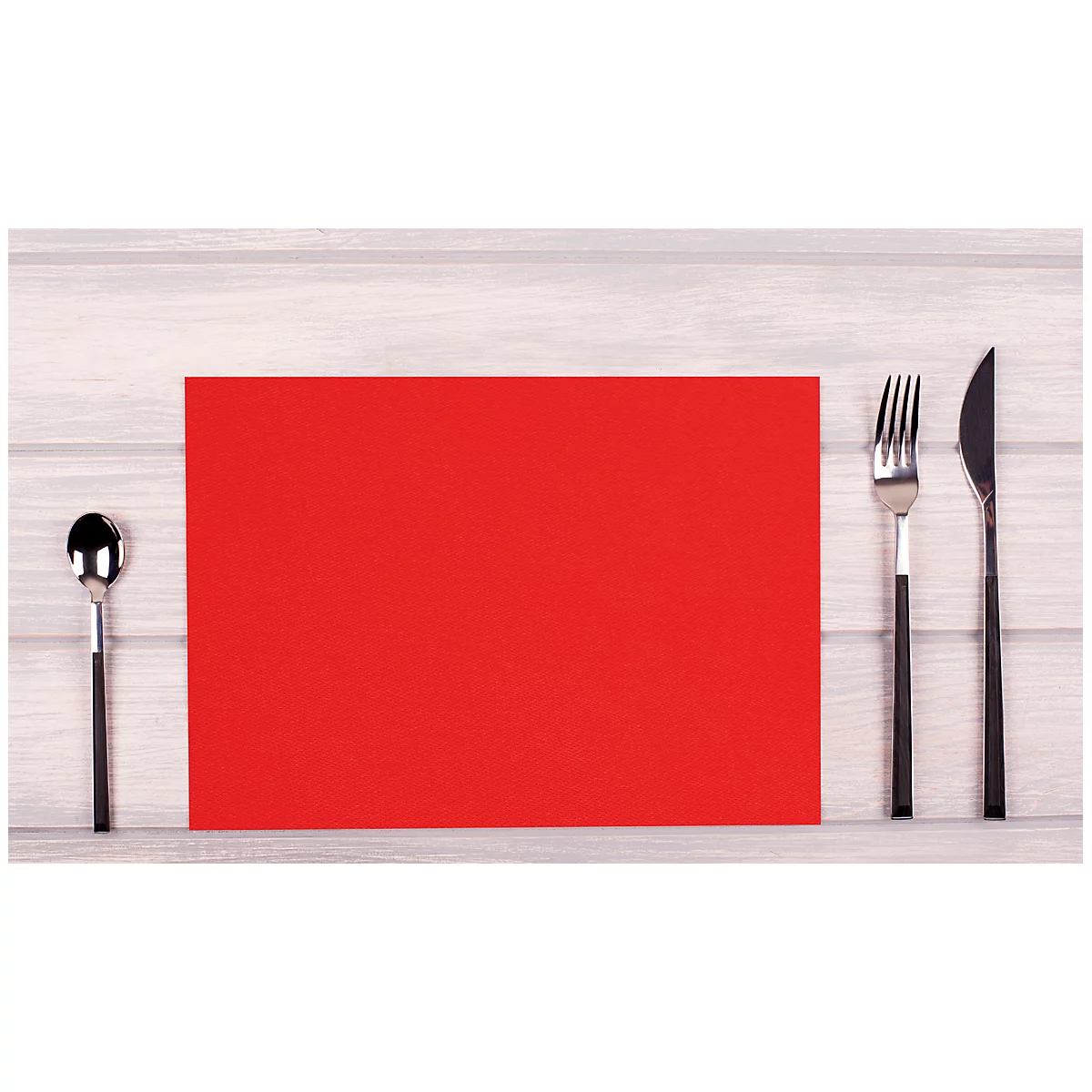 Set de table rouge avec des couverts sur fond en bois clair.