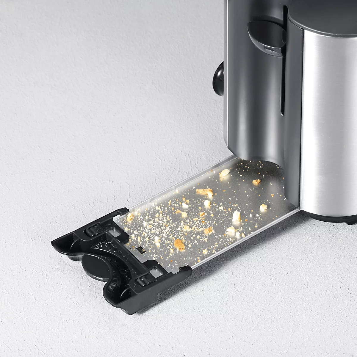 Detailaufnahme eines Toasters, bei dem die Krümelschublade teilweise herausgezogen ist und Krümel zeigt.