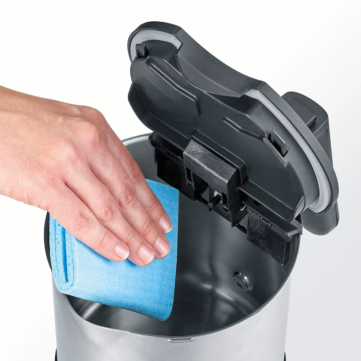 Hand wiping the inside of a kettle with a blue cloth, lid open.