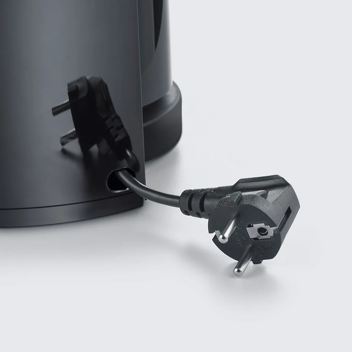 Detailaufnahme: Ein schwarzer Stecker wird in die entsprechende Öffnung eines schwarzen Wasserkochers gesteckt.