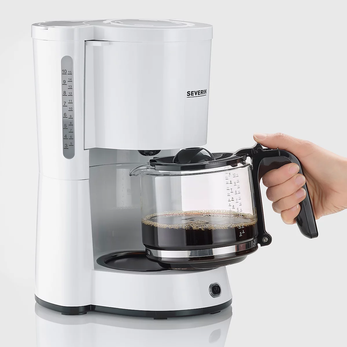 Weisse Kaffeemaschine, Person entnimmt die Kanne. Aufschrift 'SEVERIN'.