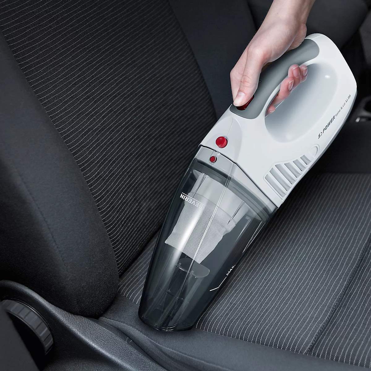 Handstaubsauger wird zum Reinigen eines Autositzes verwendet. Der Staubsauger ist weiß und grau mit rotem Knopf.