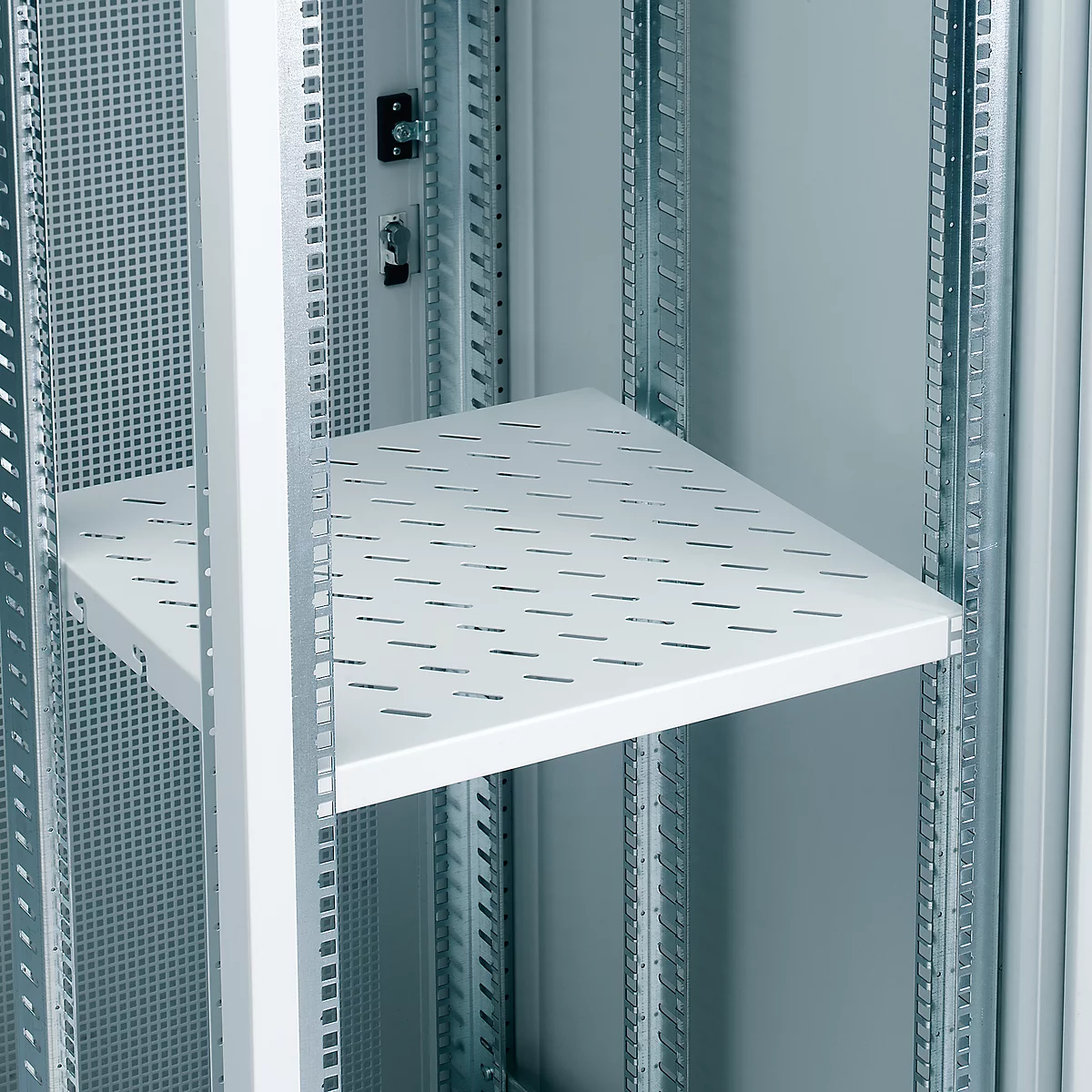 White shelf with slotted surface, mounted in a metal cabinet. Close-up of a server rack.