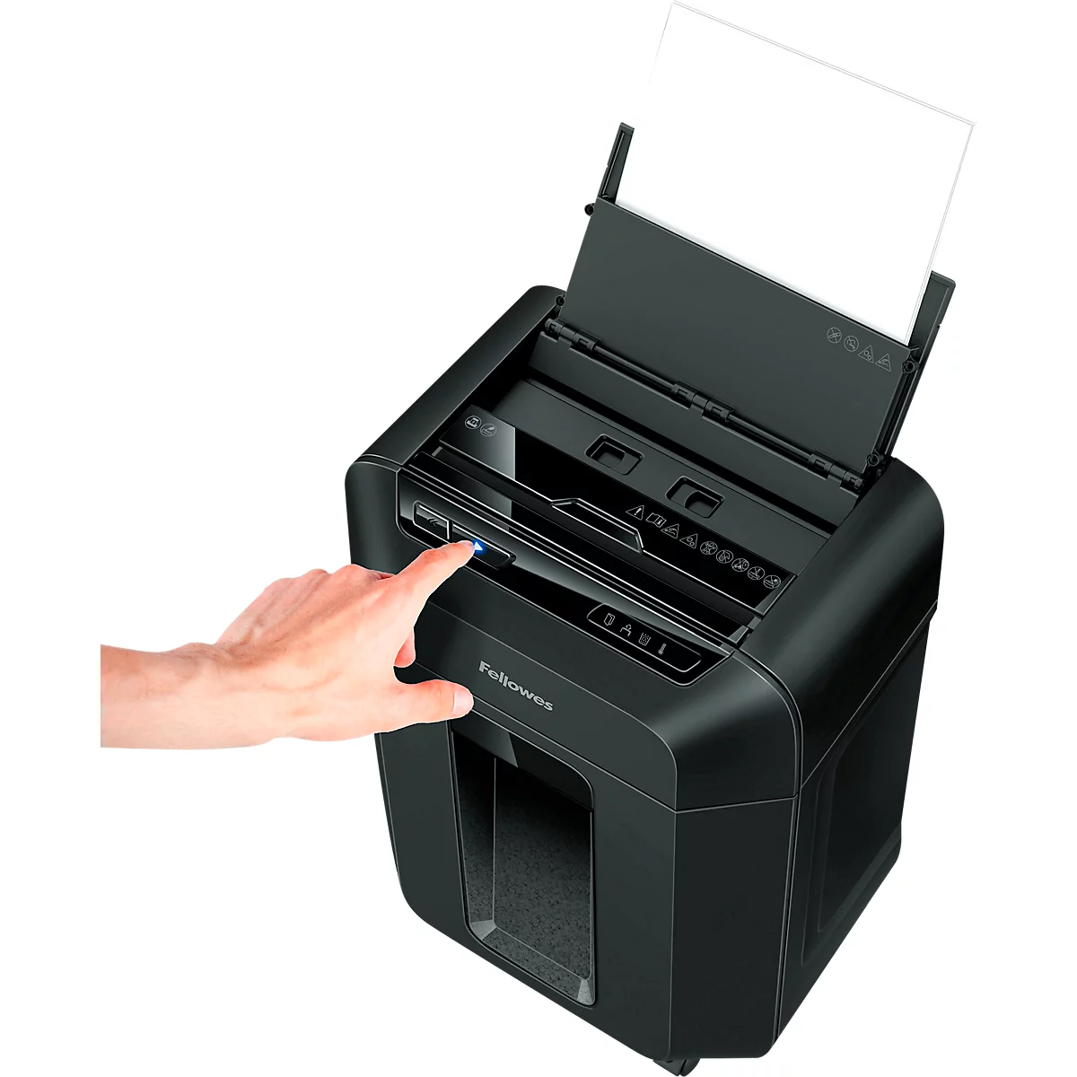 A hand presses the power button of a black paper shredder. A sheet of paper sticks out.