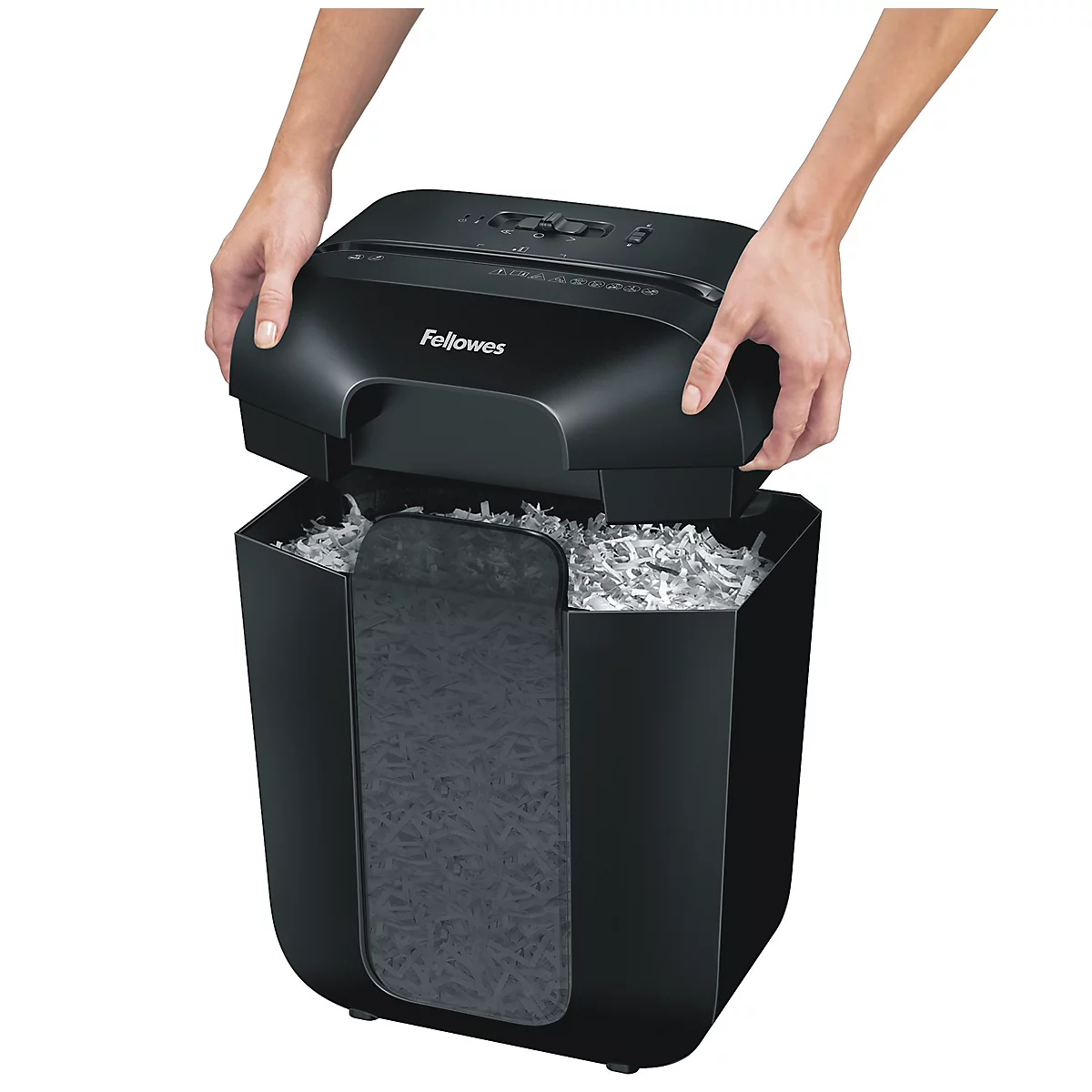 Hands lifting the top of a black paper shredder full of shredded paper. The "Fellowes" logo is visible.