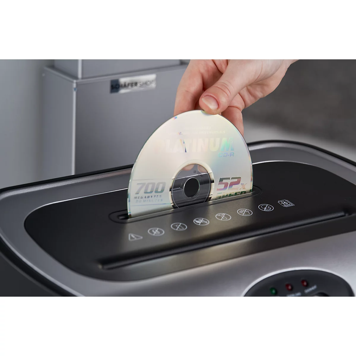 A hand places a CD into a shredder.