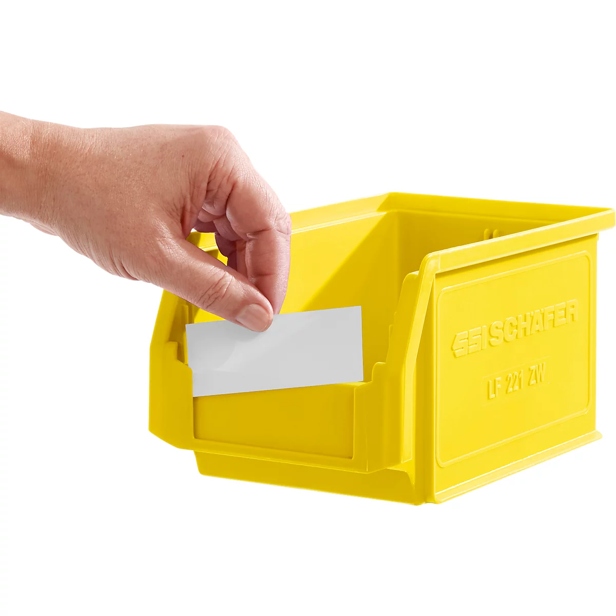 Eine Hand schiebt ein weisses Etikett in die Halterung einer gelben Sichtlagerbox von SSI Schäfer.