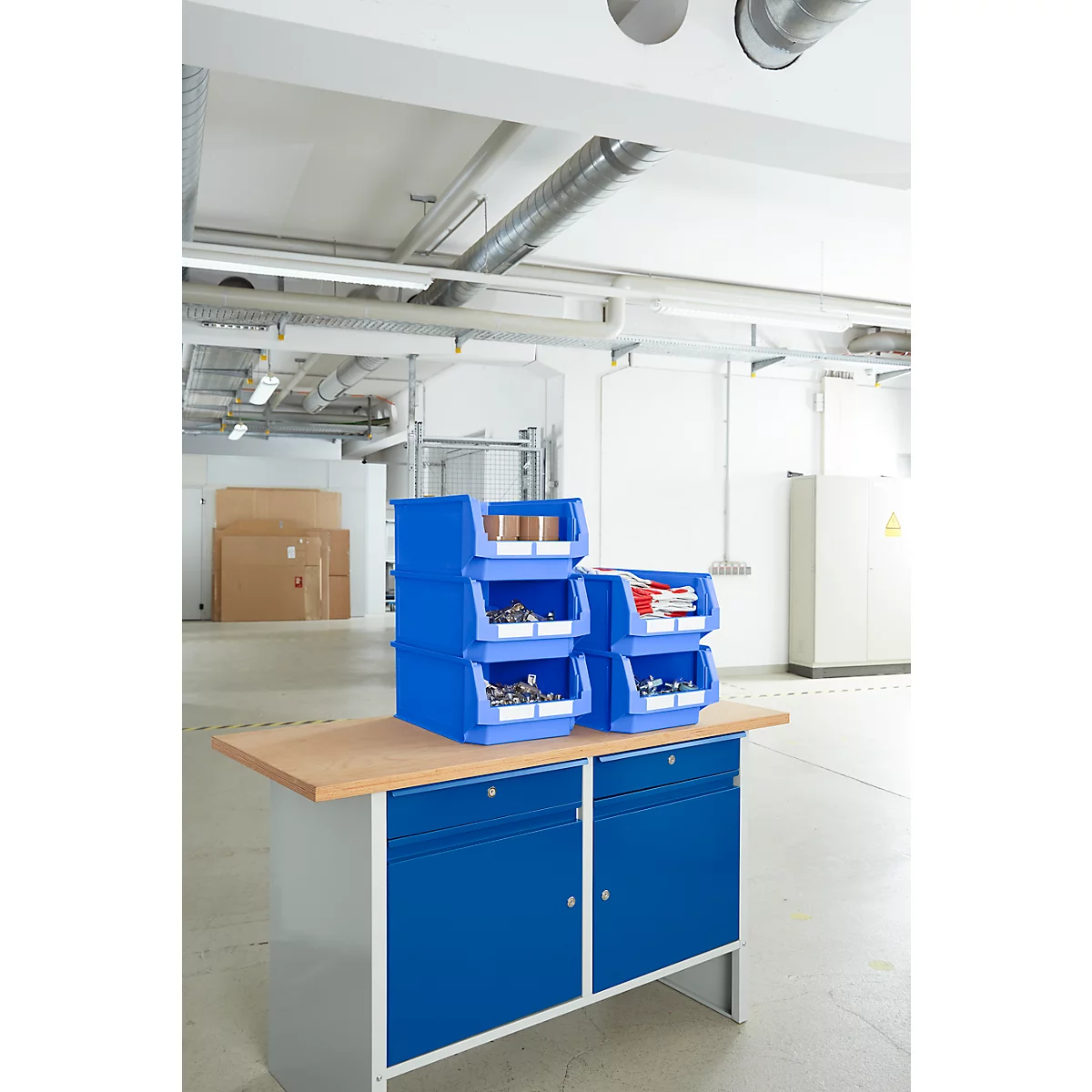 Blaue Werkzeugkästen stehen auf einer Werkbank in einem Lager. Hinter dem Werkzeug eine leere Halle.