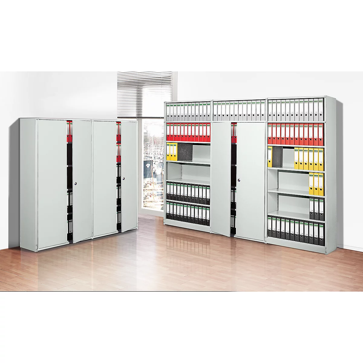Gray office cabinets, some open, filled with files in different colors, in front of a window.