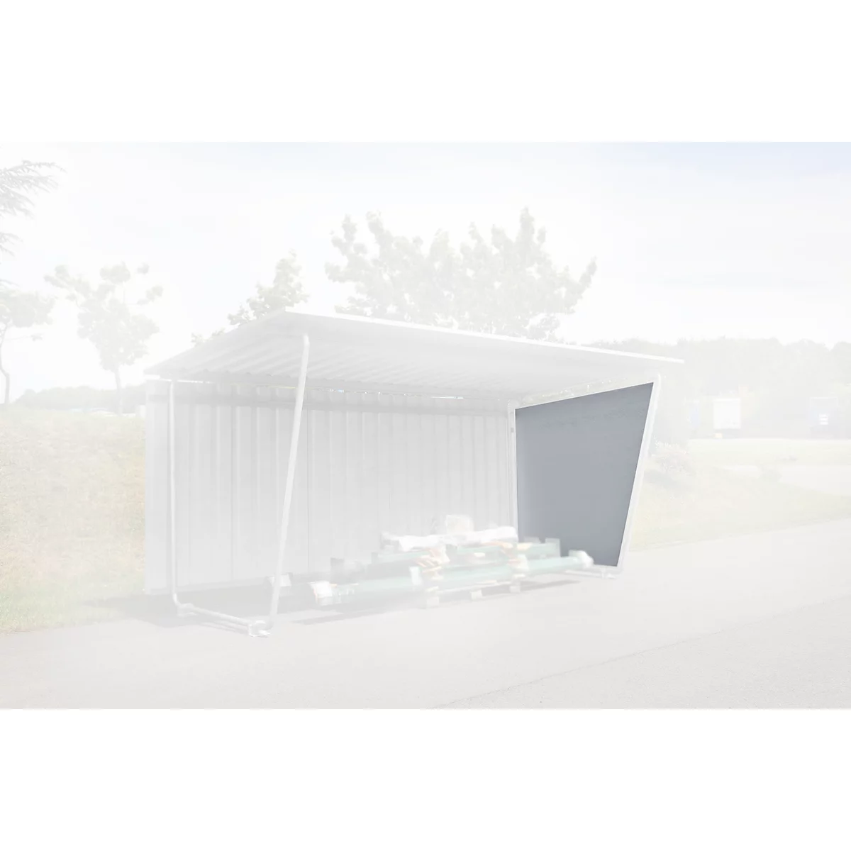 A gray outdoor shelter. It has a metal frame and a gray roof. Stacks of wood are underneath. Trees in the background.