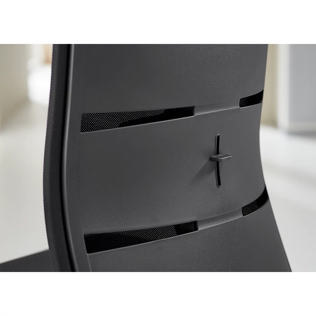 Gros plan d'une chaise noire. Un détail en forme de croix et des inserts en mesh sont visibles.