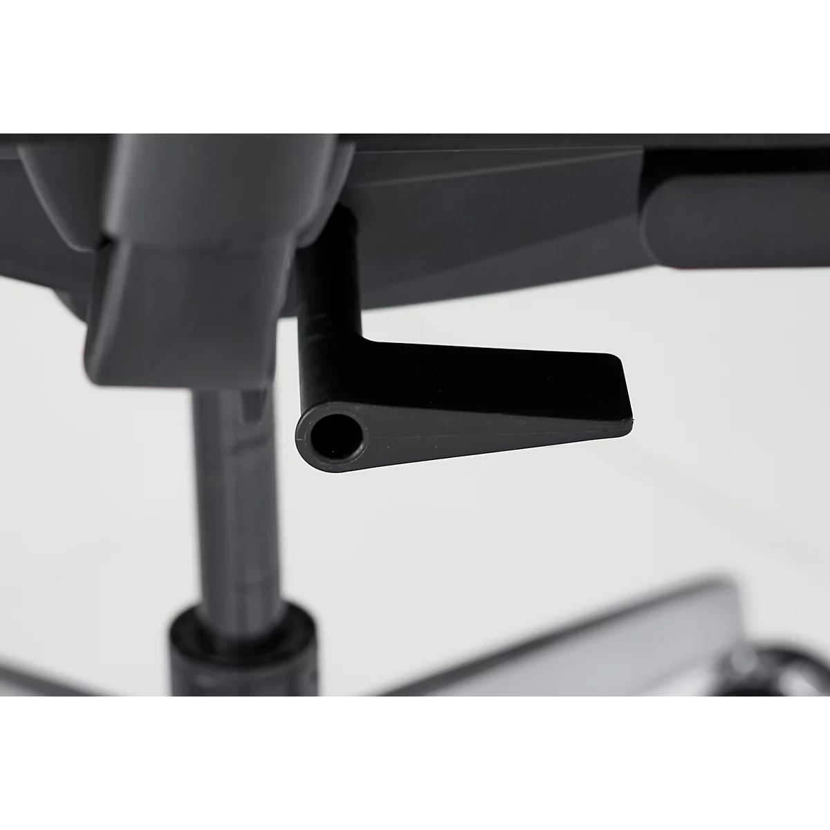 Gros plan du levier noir sous une chaise de bureau, pour régler la hauteur de l'assise.