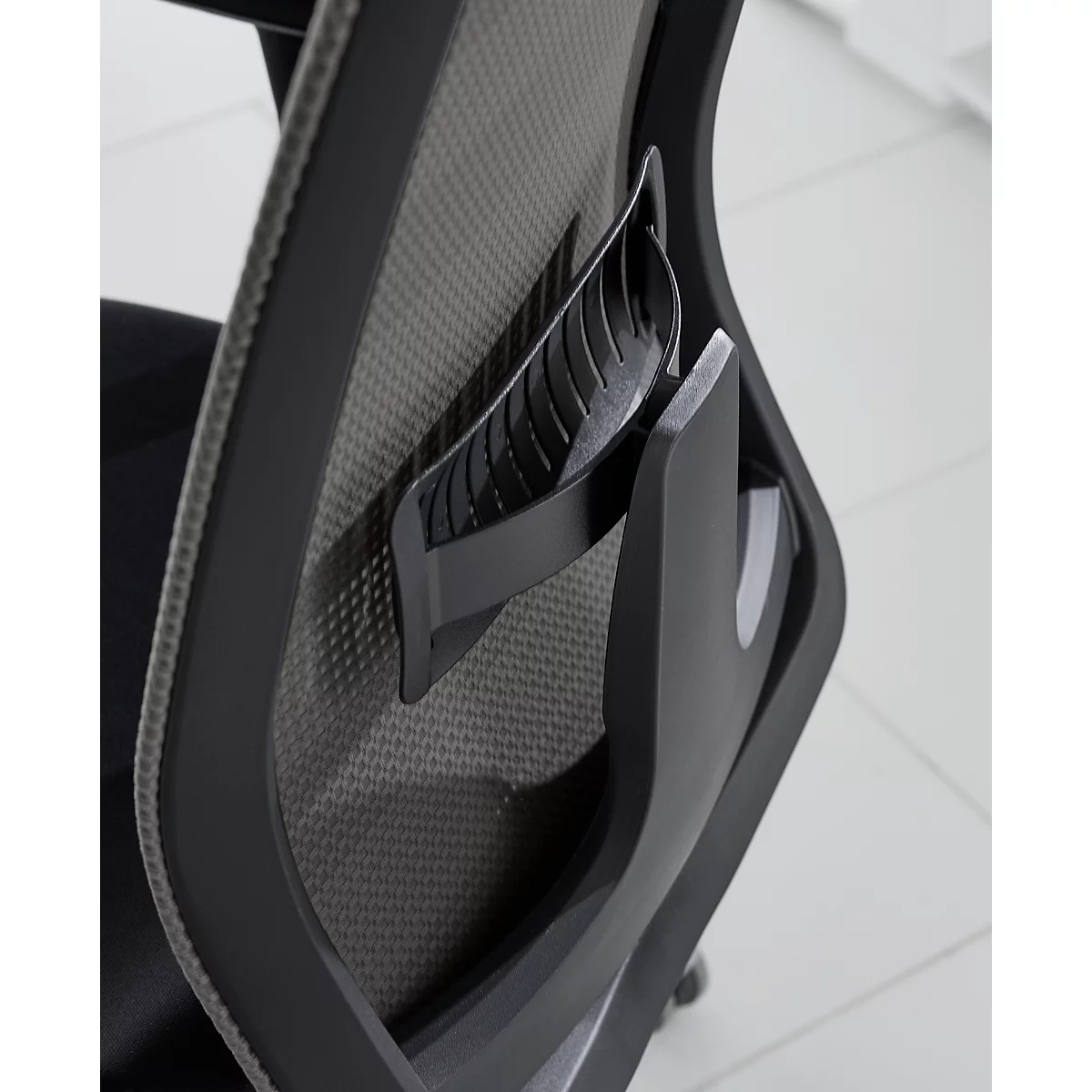 Gros plan d'un dossier de chaise de bureau noir avec tissu en maille grise. Focus sur le support lombaire.