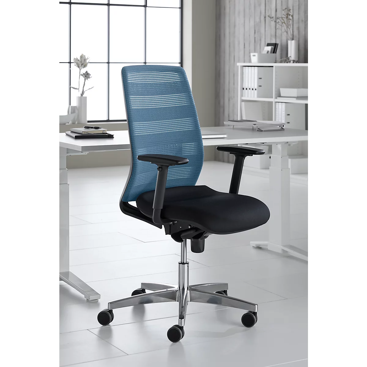 Chaise de bureau avec dossier en filet bleu et assise noire. Les accoudoirs sont noirs. La chaise est sur un cadre chromé.