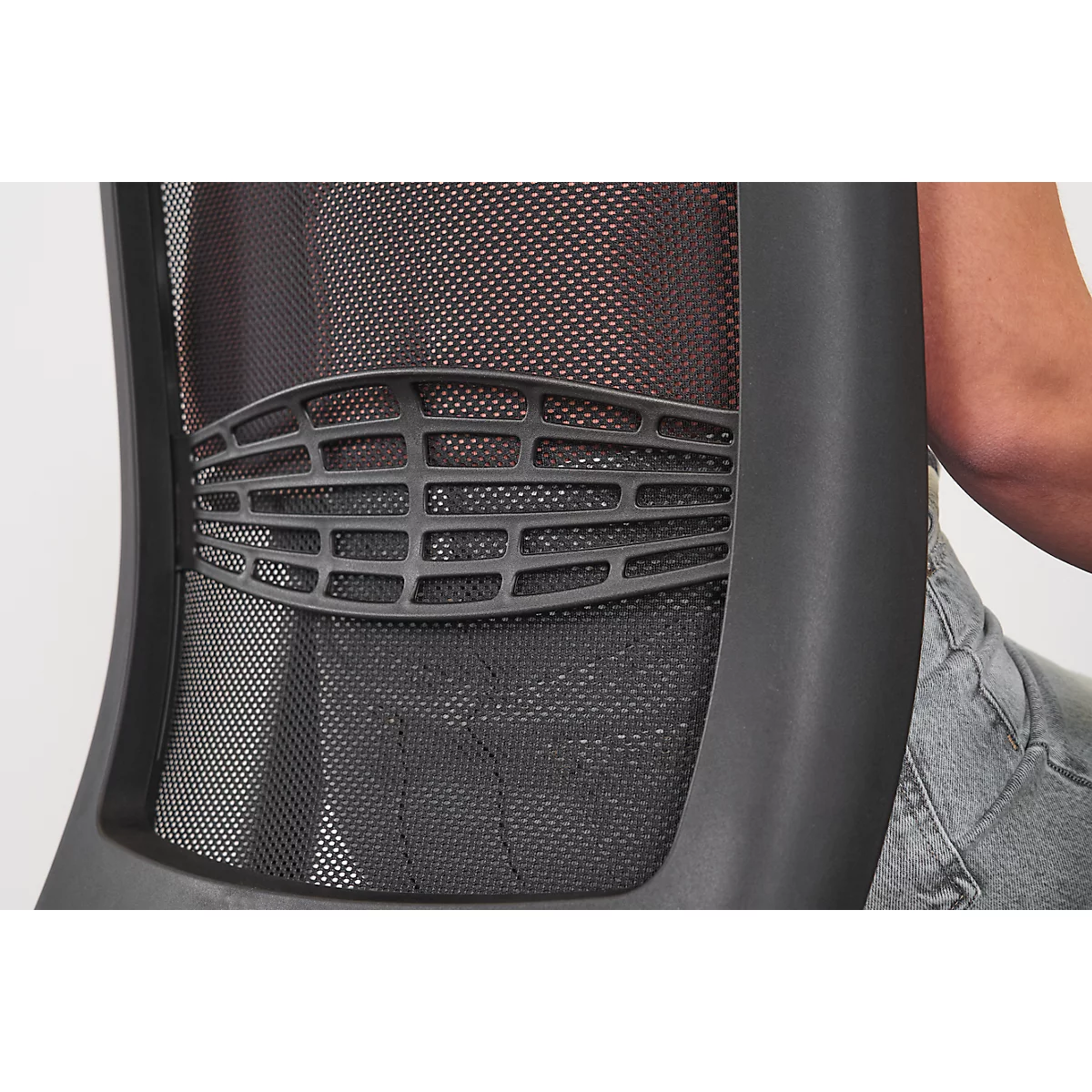 Gros plan sur le support lombaire ergonomique d'un dossier de chaise de bureau en maille noire.