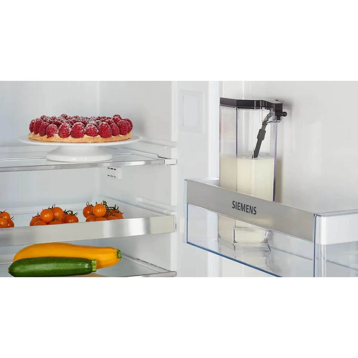 Offener Kühlschrank: Himbeerkuchen, Gemüse und Milchspender. Auf dem Fachboden liegen Tomaten, Zucchini und eine gelbe Zuccini. Der Milchspender zeigt Siemens Logo.