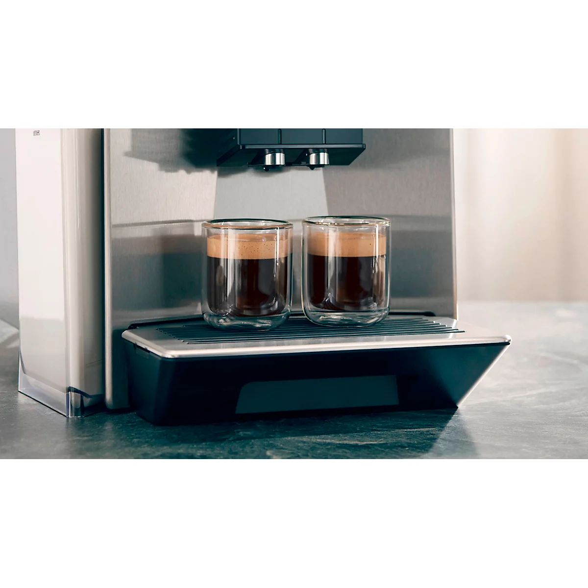 Zwei Gläser Espresso stehen auf einer Kaffeemaschine. Das braune Getränk ist in Gläsern aus Doppelwandglas zu sehen.
