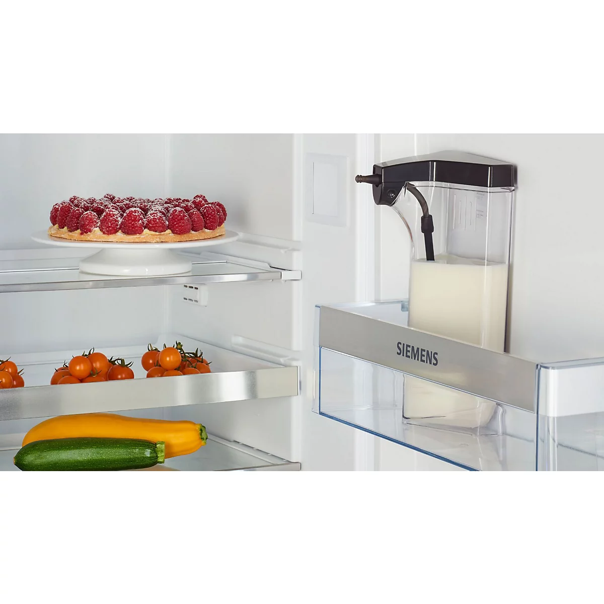 Kühlschrank mit Kuchen, Gemüse und einem Milchspender. Siemens-Schriftzug.