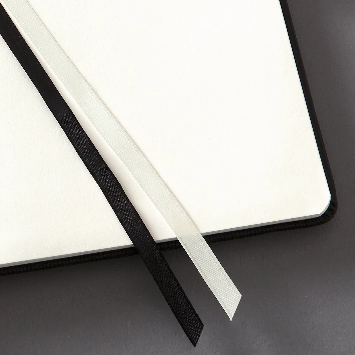 Gros plan sur un carnet ouvert. Marque-pages noir et blanc sur les pages blanches.