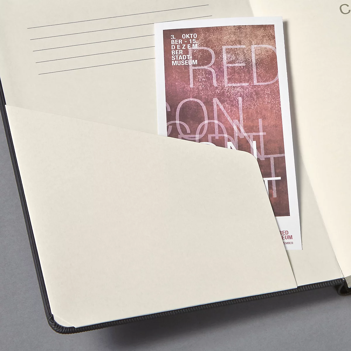 Un cahier ouvert avec une carte dans la poche intérieure. La carte indique "RED ON ART".
