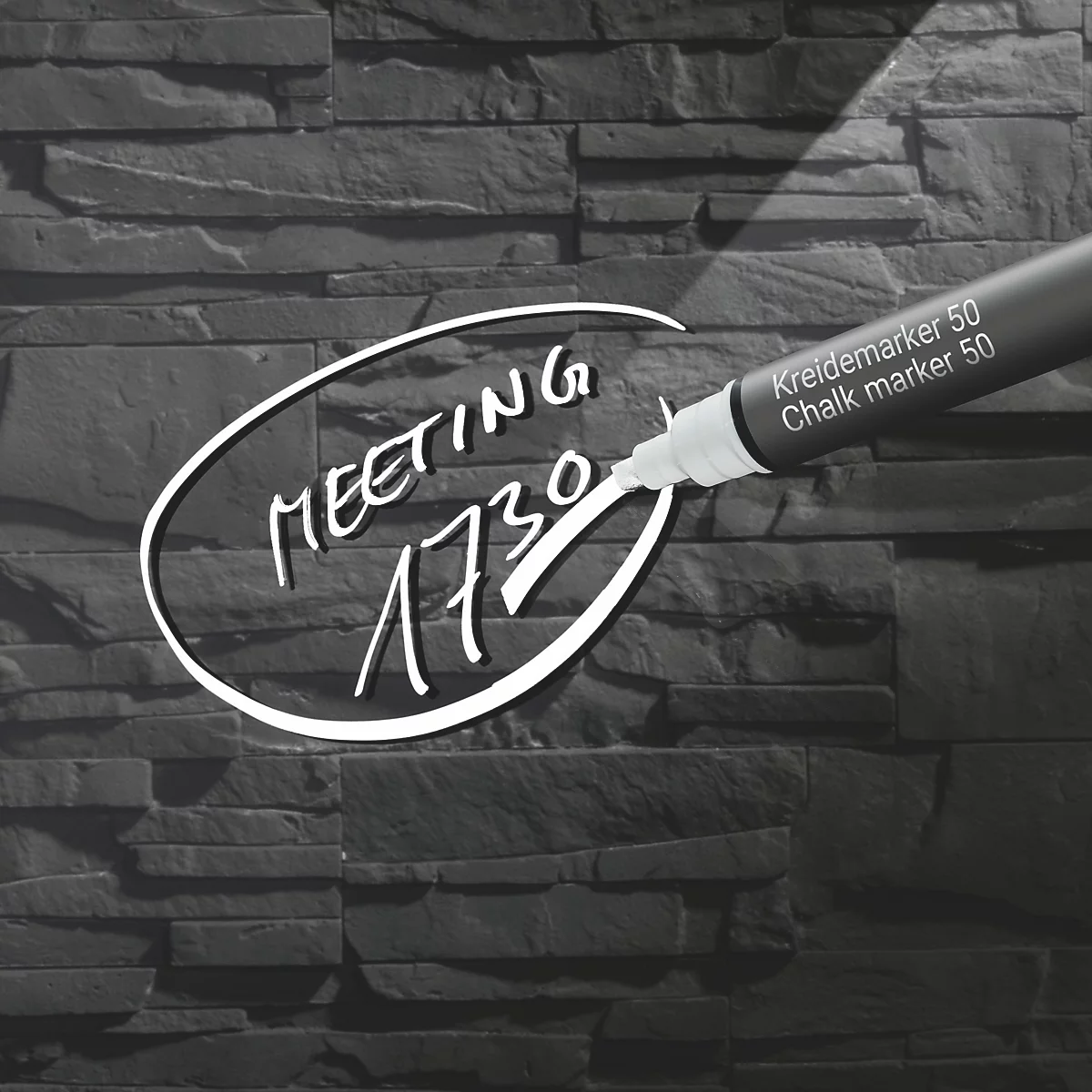 Een pen schrijft het woord meeting om 17:30 uur op een stenen muur. Rechts staat Kreidemarker 50.