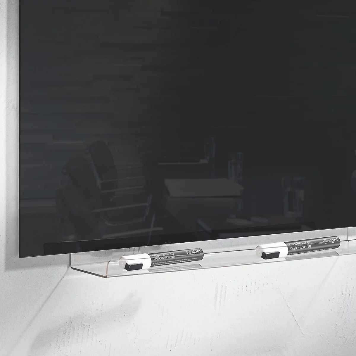Een zwart glazen magnetisch bord met twee pennen. Op de achtergrond zijn stoelen en tafels te zien.