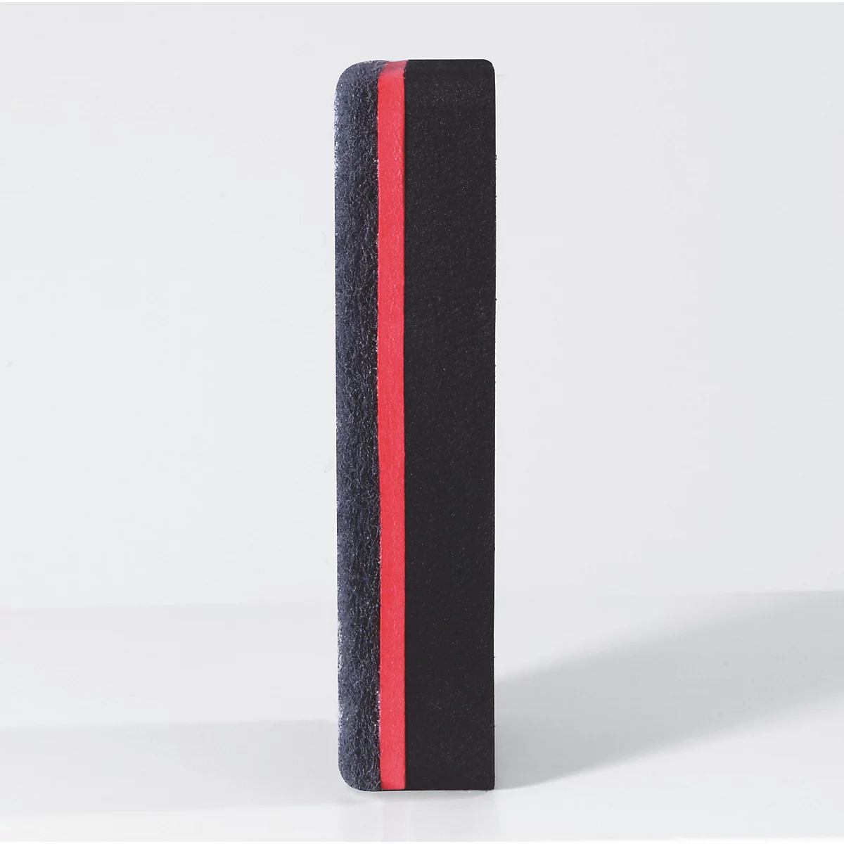 Une gomme noire avec une ligne rouge, vue de côté.