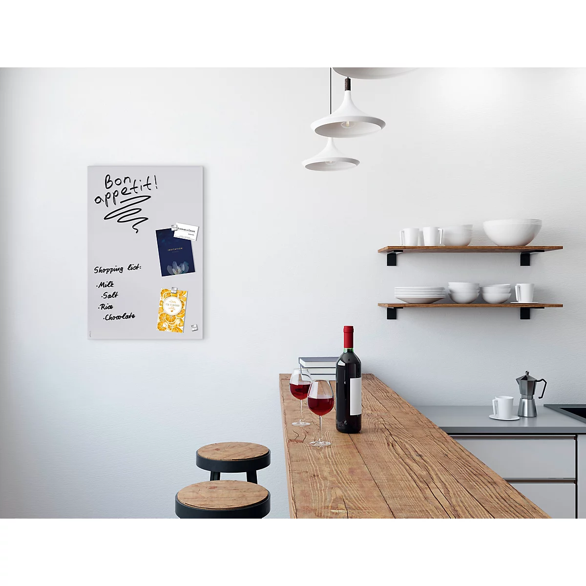 Eine Küche mit hellen Wänden, Holztisch und Weinflaschen. Ein Whiteboard hängt an der Wand mit Notizen und Magneten.