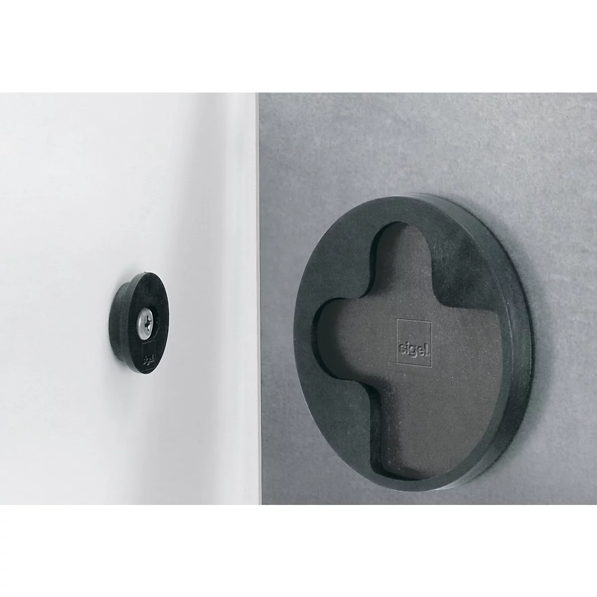 Zwei schwarze, runde Objekte an Wänden. Eines ist klein und rund, das andere gross mit einem Kreuz in der Mitte.