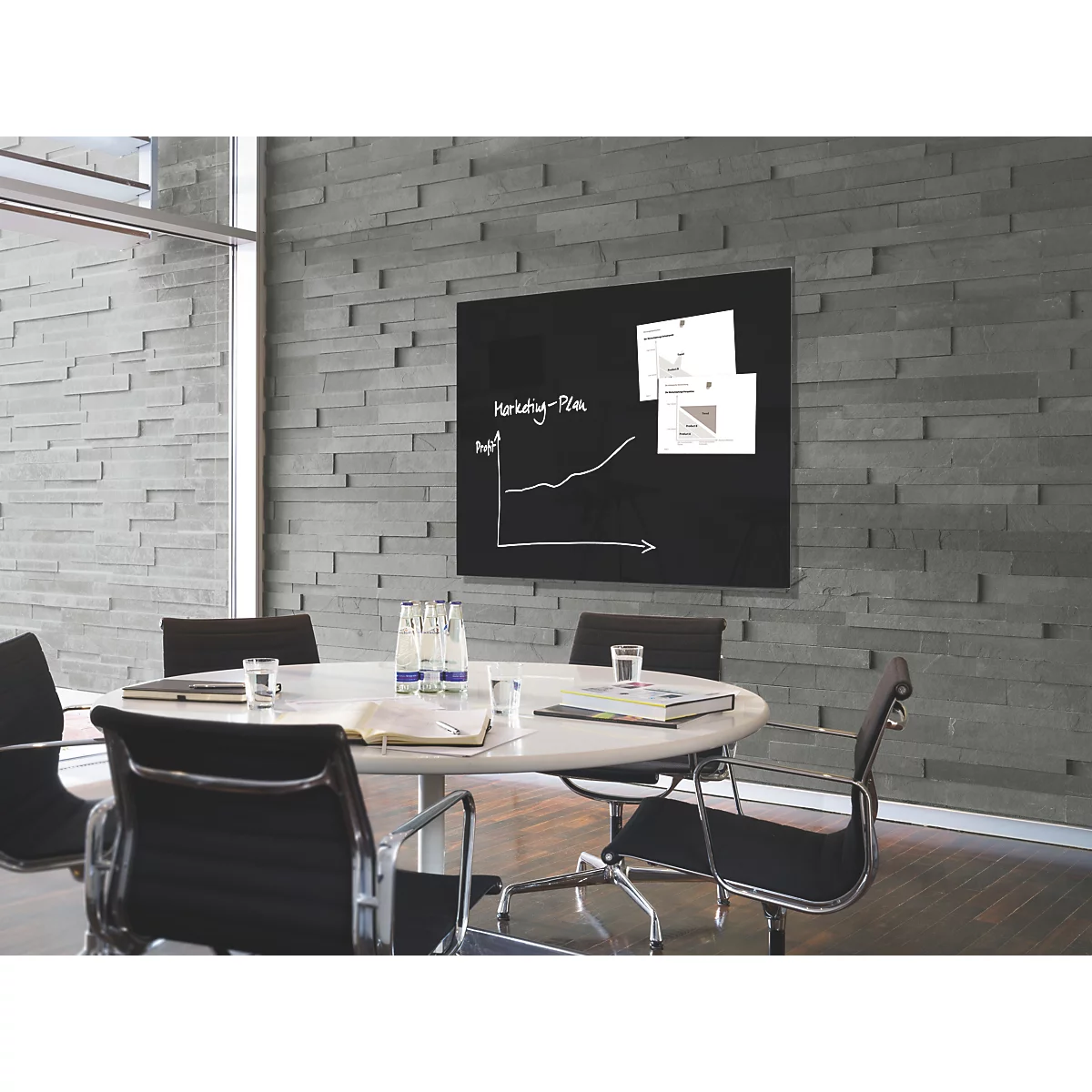 Konferenzraum mit Tafel, Diagrammen und Tisch, auf dem Wasserflaschen stehen.