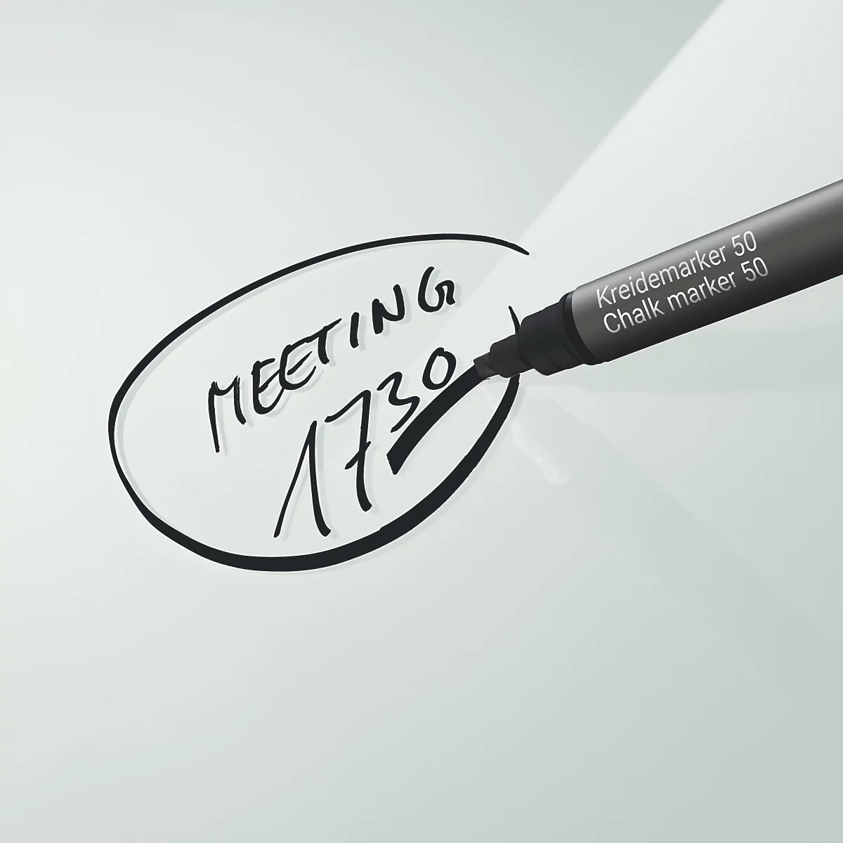 Ein schwarzer Kreidemarker schreibt "Meeting 1730" in eine ovale Form. Oben steht "Kreidemarker 50", darunter "Chalk marker 50".