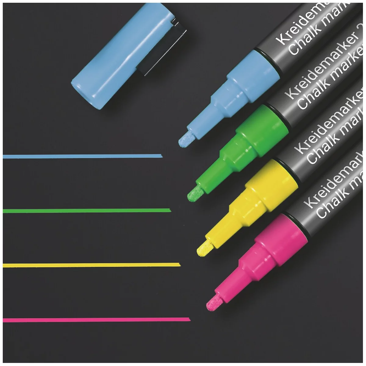 Auf schwarzem Hintergrund liegen farbige Kreidemarker und Linien. Blauer Stift mit geöffneter Kappe. Grün, Gelb und Pink.
