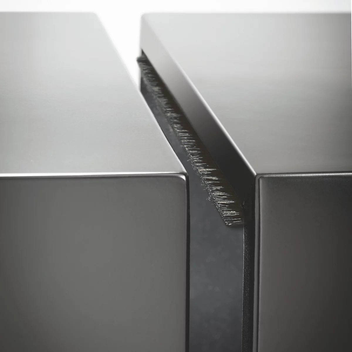 Close-up van twee metalen oppervlakken gescheiden door een smalle opening. De opening heeft een ruw, geborsteld oppervlak.