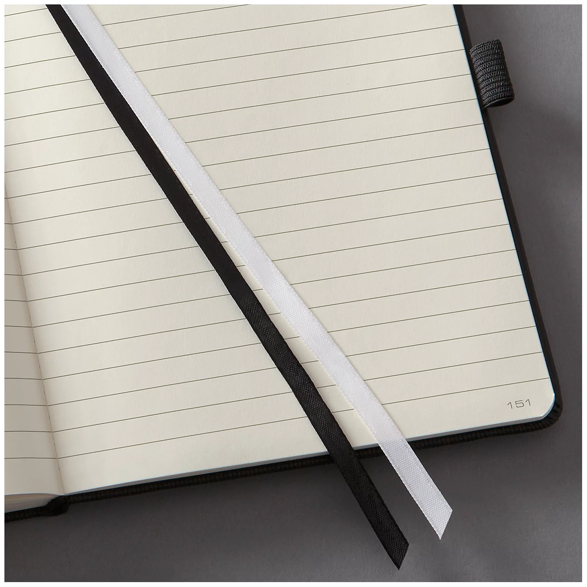 Opened notebook with lined page. A black and a white ribbon are inside.