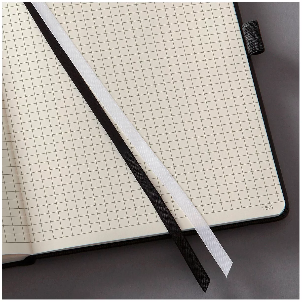 Notebook with graph paper pages and two bookmarks in black and white.
