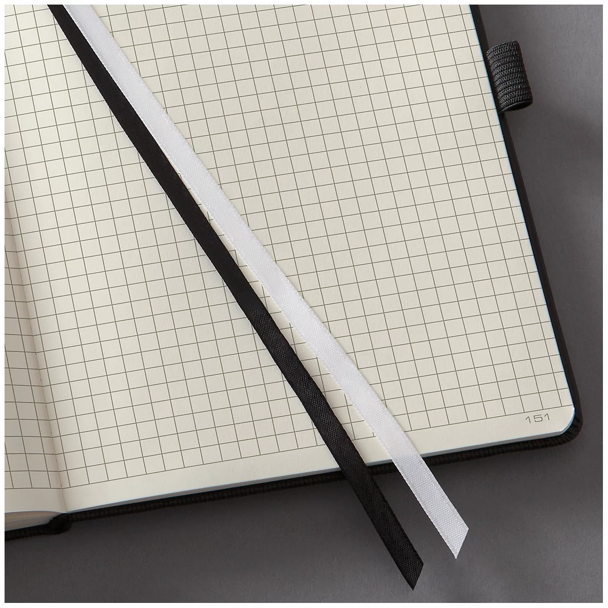 Open notebook with grid pages, black and white bookmark. The spine is made of black fabric.
