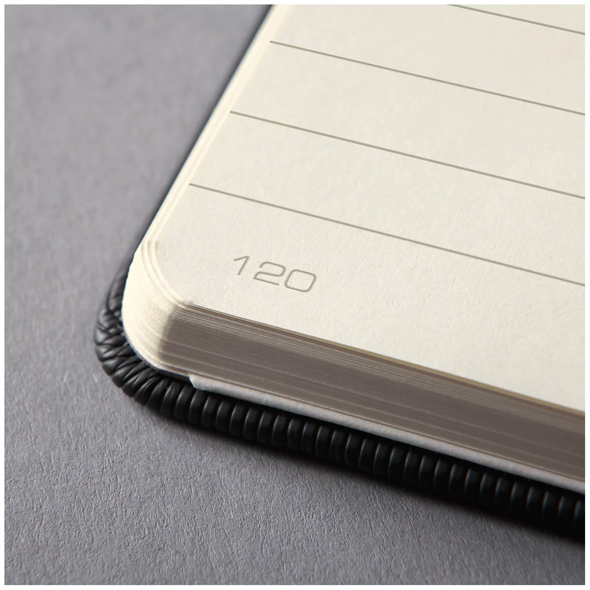 Close-up of a notebook opened at the side. The page shows the number 120, next to it lines for notes.