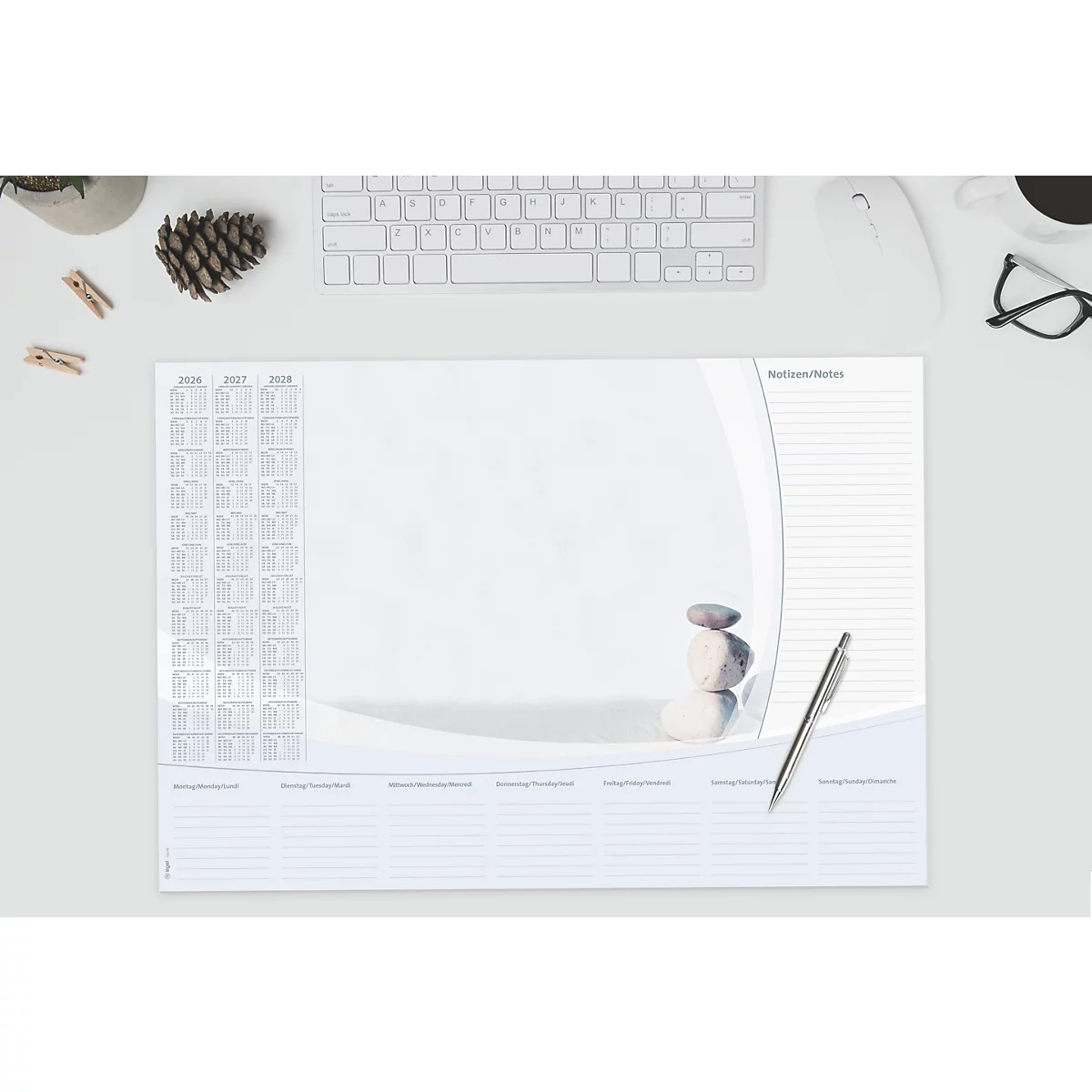 Schreibtischunterlage mit Kalender und Stein-Dekoration, Stift und Tastatur, minimalistisch.