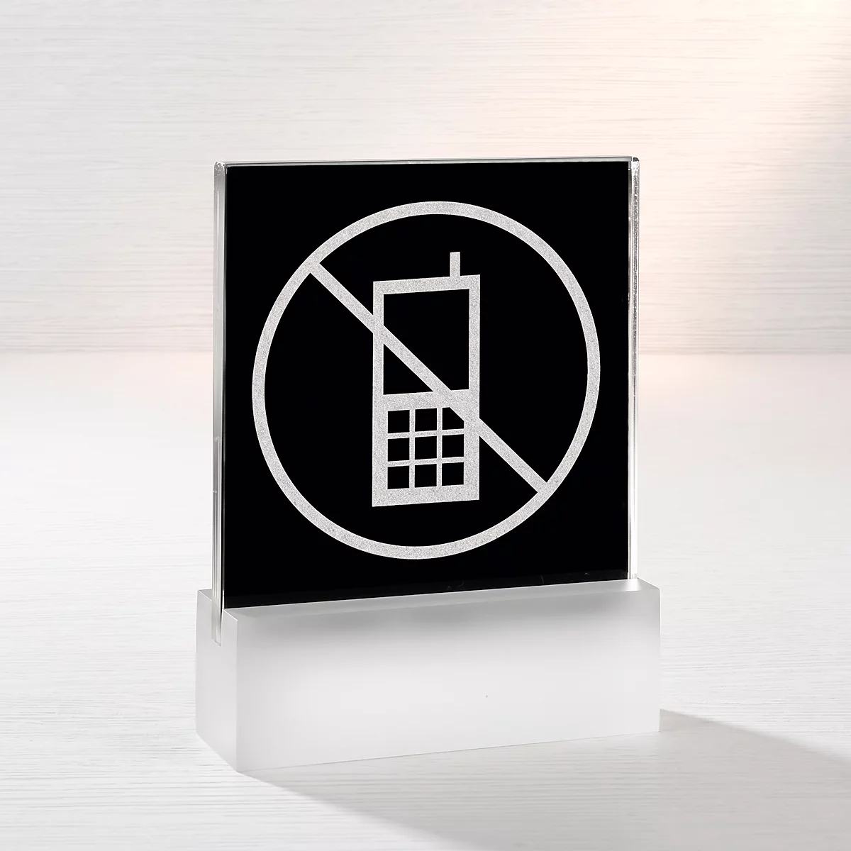 Quadratisches Schild auf weissem Sockel mit durchgestrichenem Handy-Symbol als Verbotshinweis.