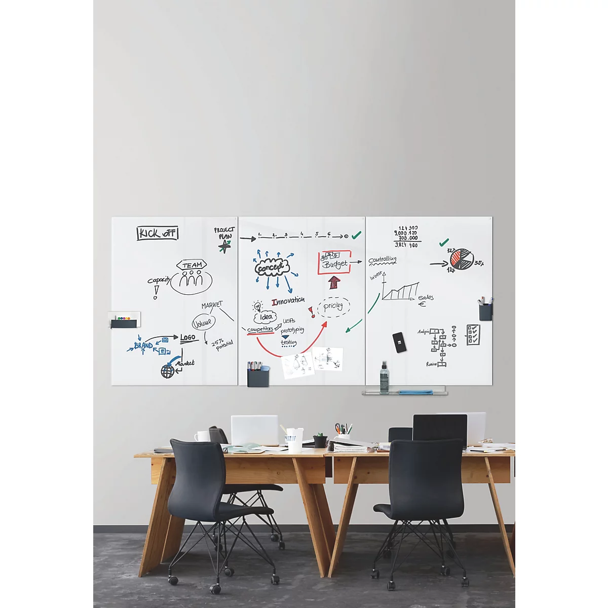 Trois tableaux blancs avec des notes sur un mur en bois, avec des bureaux et des chaises en dessous.