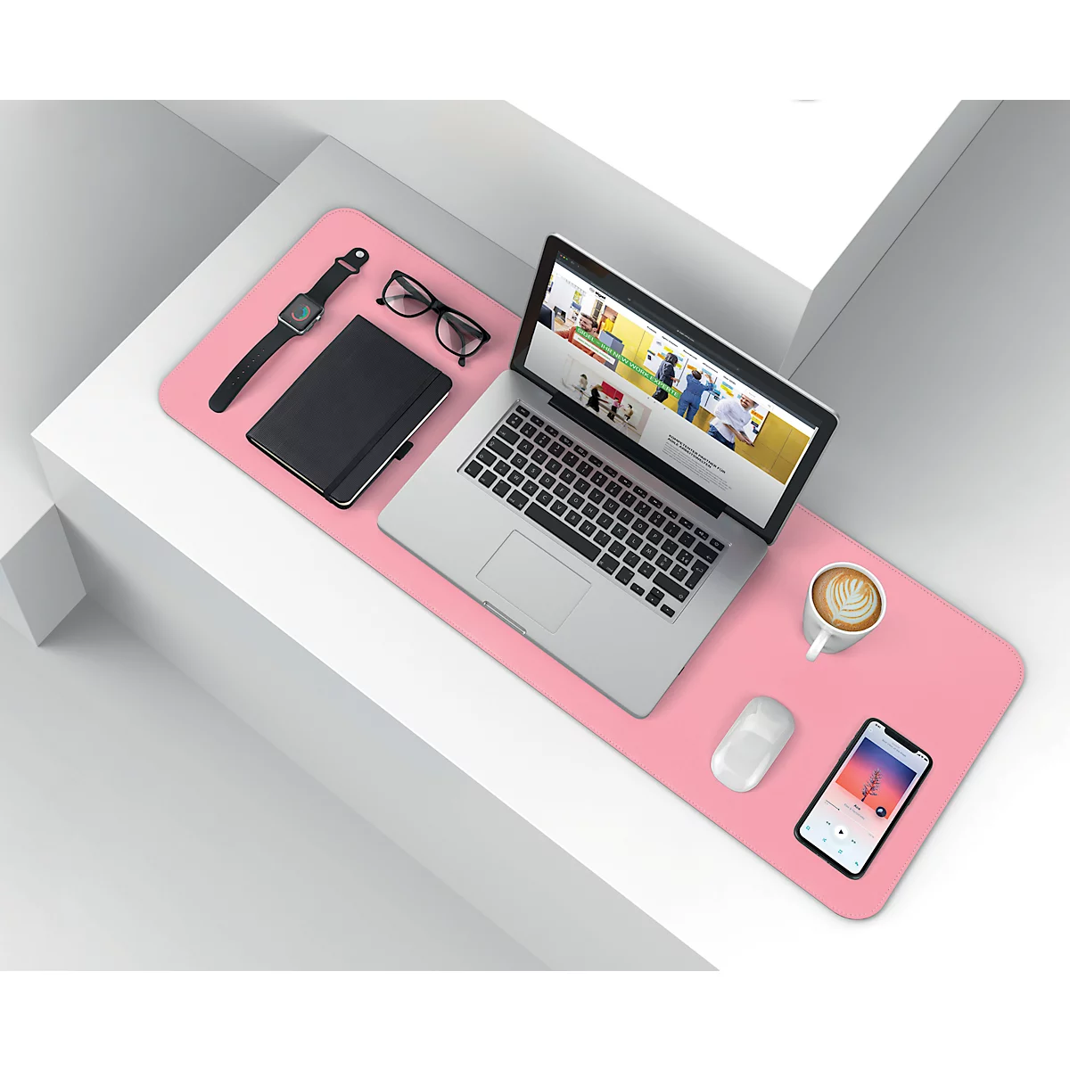 Rosa Schreibtischunterlage mit Laptop, Smartphone, Uhr, Brille und Kaffeetasse. Auf weißem Podest.