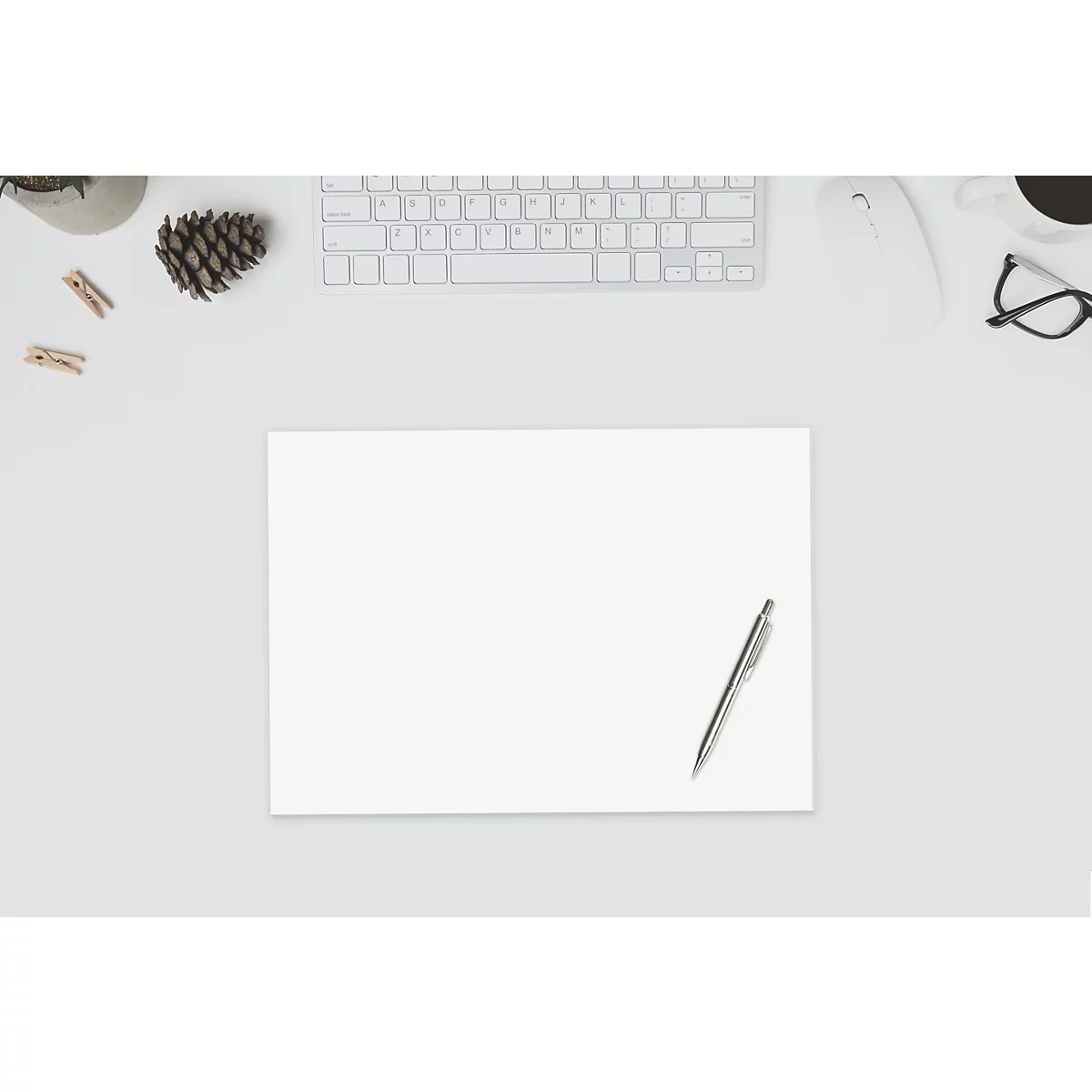 Draufsicht auf einen Schreibtisch mit Papier, Stift, Tastatur, Maus, Brille, Kaffee und Dekoration.