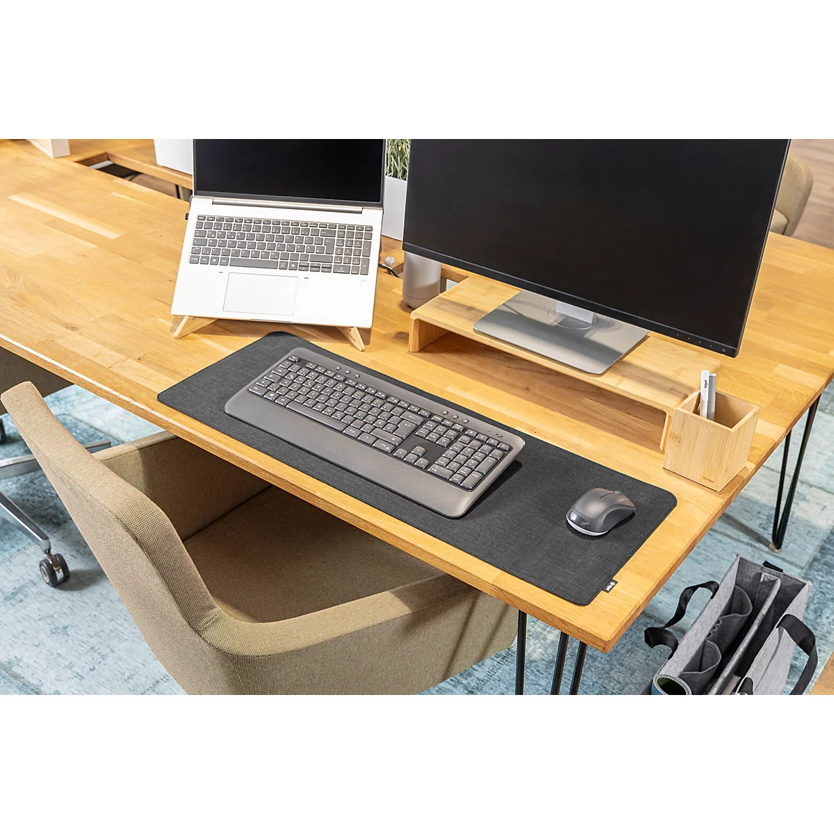Büroarbeitsplatz: Holzschreibtisch mit Laptop, Bildschirm, Maus, Tastatur und Stiftehalter.