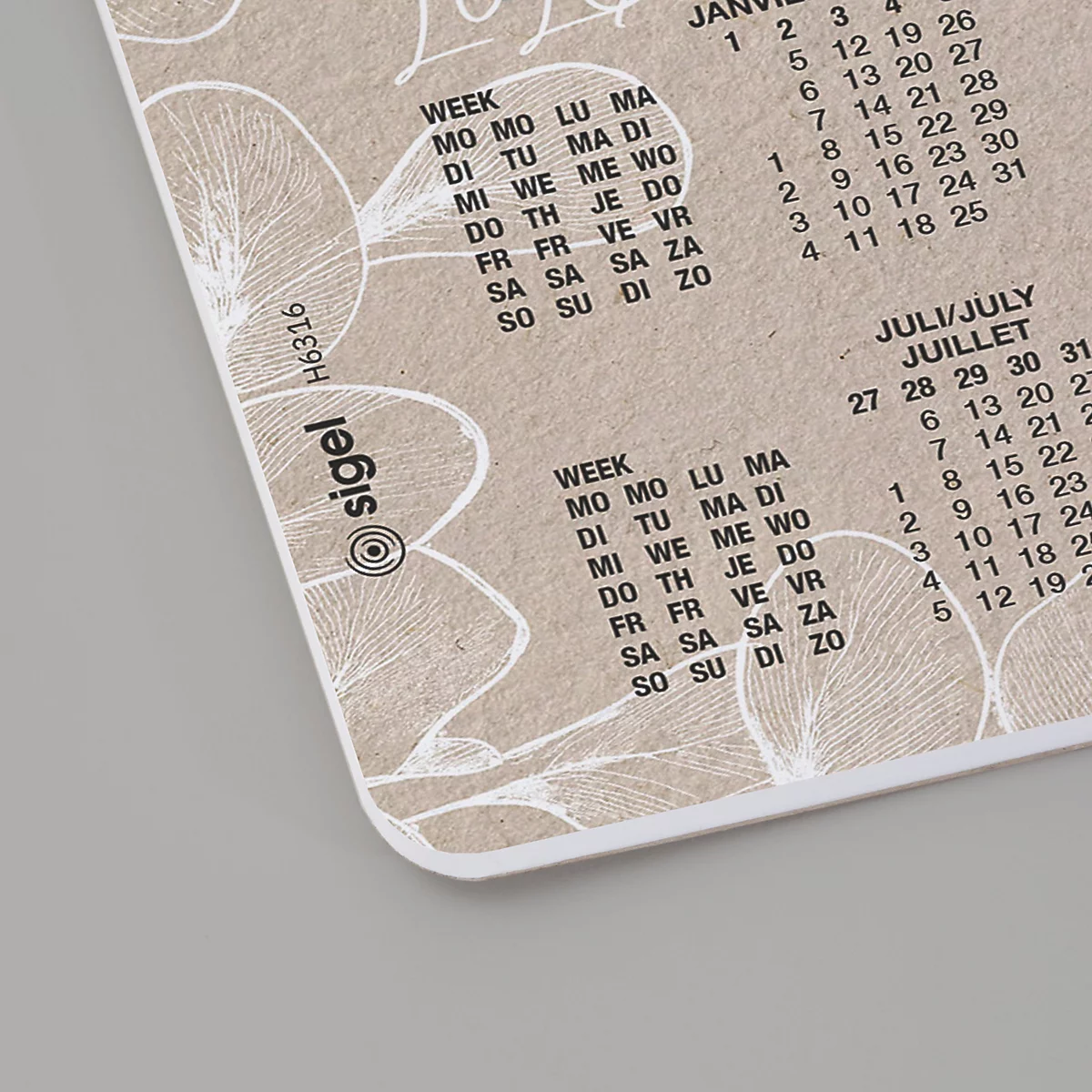 Close-up van een beige kalender met bloempatronen die de maanden januari en juli weergeven met weekdagen en datums.