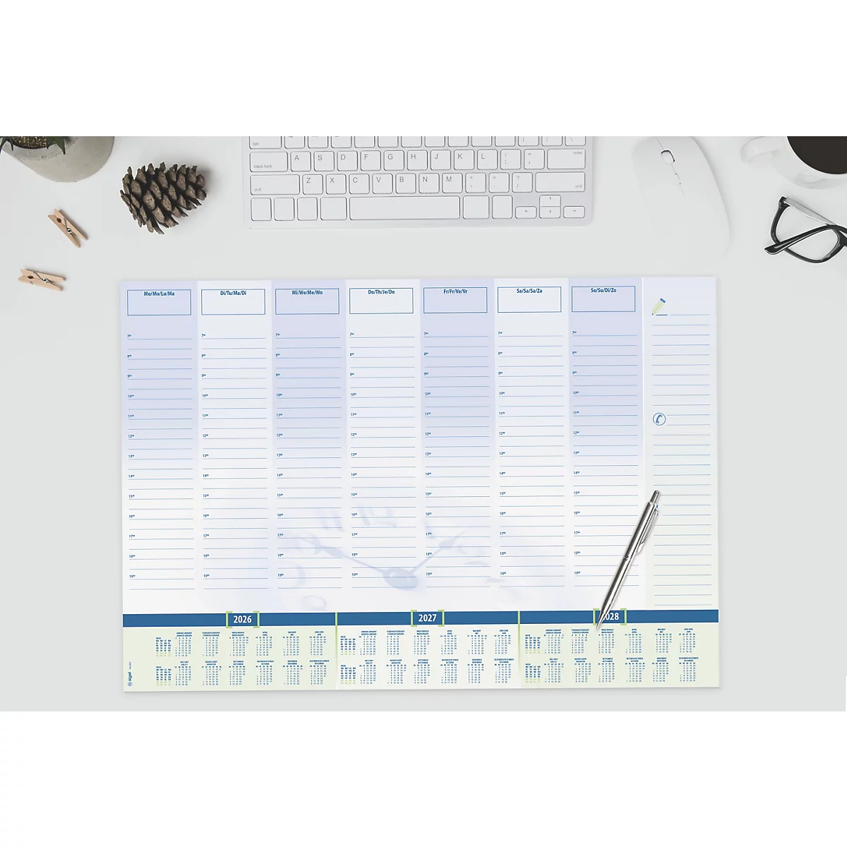 Lichtblauwe wekelijkse bureaubladkalender, pen, toetsenbord, bril, dennenappel en decoratie.